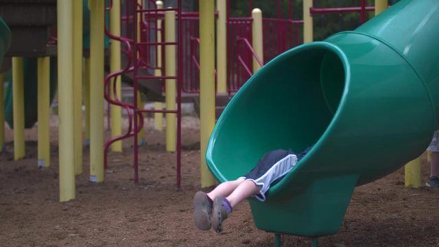 A boy going down a slide and coming out feet first with a smile.  Shot on a Blackmagic Ursa Mini Pro 4.6k with a Sigma 50-100mm f/1.8.