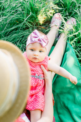 Portrait of a beautiful, laughing girl with gorgeous blue eyes being held by her mother, on her back, in her lap in the garden