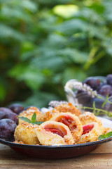 Plum dumplings coverder with breadcrumb and sprinkled with sugar, vertical. Outdoor image, in the garden.