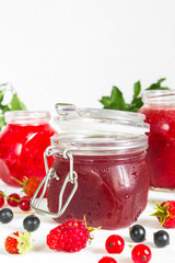assortment of jams, seasonal fresh berries and fruits on white background