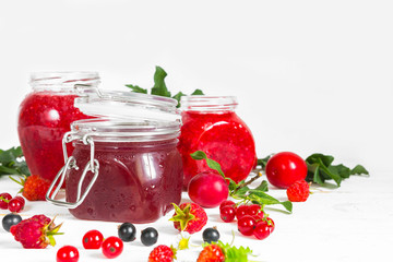 assortment of jams, seasonal fresh berries and fruits on white background