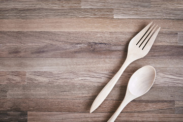 Wooden craft fork and spoon on the wooden floor with texture background with copy space