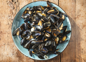 Mussels cooked in white wine/Blue plate with mussels cooked in white wine on rustic wooden...