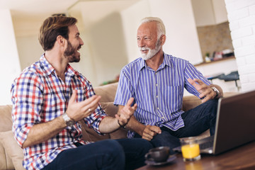 Adult Son Helping Senior Father With Computer At Home