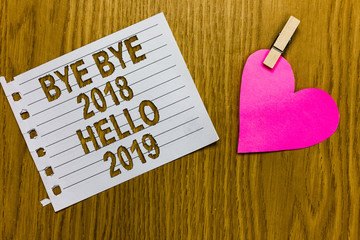Conceptual hand writing showing Bye Bye 2018 Hello 2019. Business photo showcasing Starting new year Motivational message 2018 is over Yellow woody deck word with white page paper clip grip heart. © Zofia