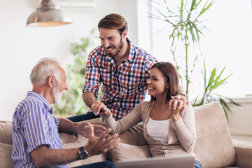 Young couple talking with their senior father at home