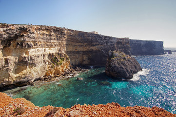 Fototapeta na wymiar Blue lagoon with high cliffs and Santa Marija Tower on Commino Island in Malta (Torri ta' Kemmuna)