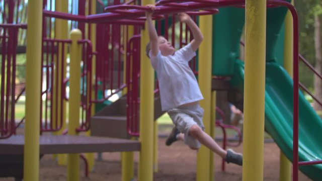 Slow-motion footage of a boy going back and forth on monkey bars at a park.  Shot on a Blackmagic Ursa Mini Pro 4.6k with a Sigma 50-100mm f/1.8.