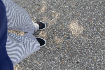 Fashion photo selfie of feet. Sneaker shoes and trousers on the road, top view