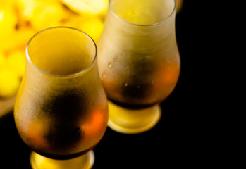 glass of whiskey with ice cubes and salty snacks on the background of the bar