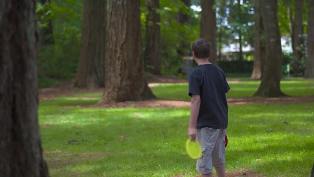 Slow-motion footage of a boy teeing off in frisbee golf, watching his throw and celebrating it when it lands.  Shot on a Blackmagic Ursa Mini Pro 4.6k with a Sigma 50-100mm f/1.8.