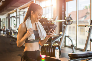 Young fit woman using smart phone at gym