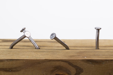 Steel nails, straight and crooked, hammered into a wooden board