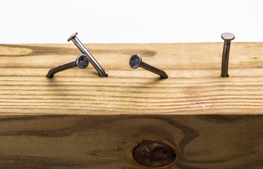 Steel nails, straight and crooked, hammered into a wooden board