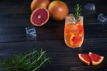 Refreshing cold cocktail with grapefruit and rosemary on a black background, Top view.