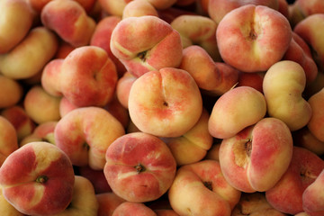 Fresh Donut peaches, also known as Saturn peaches, at a farmer's market.
