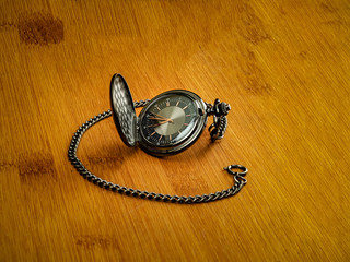 Black pocket watch resting on wood table