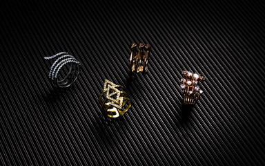 Golden, silver and bronze rings collection on black textured paper
