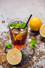 Traditional ice tea, chilled, with lemon, mint and ice on rustic table
