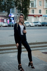 Girl in black trousers and jacket.The blonde in the black suit.Blonde posing in the city