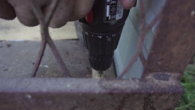 A close-up slow motion shot of an electric drill screwing a screw