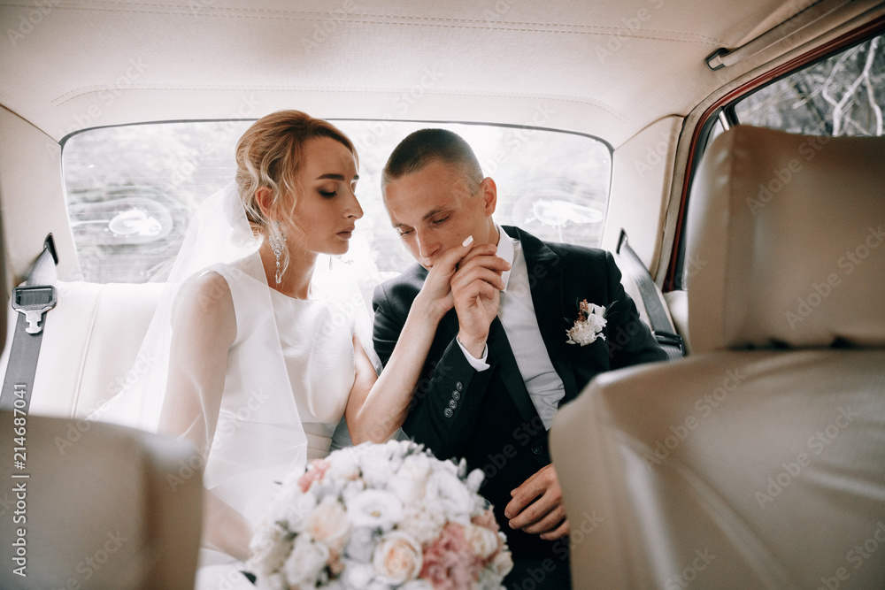 Wall mural Wedding photo in the car.The bride and groom in a retro car.