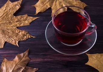 Cup of tea with leaves on a black wooden background.