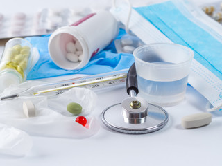 Pills, mask, thermometer and stethoscope on white background.