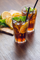 Traditional ice tea, chilled, with lemon, mint and ice on rustic table