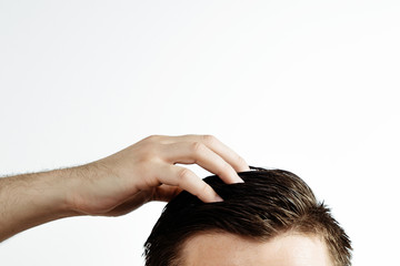 Hand on a man's hair on a white background. A view of brown hair with side hairline isolated on a white background.