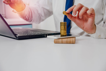 Gold coins are on the phone. The concept of financial growth, earning thanks to telephone, mobility. The man is adding a gold coin to the pile of gold coins. Profit increase.