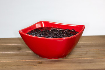 Red bowl filled with black bean soup ready to eat on the kitchen table