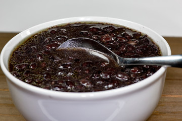 White bowl filled with black bean soup and a spoon ready to eat on the kitchen table