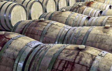 Old and stained wooden wine barrels in rows inside a wine cellar