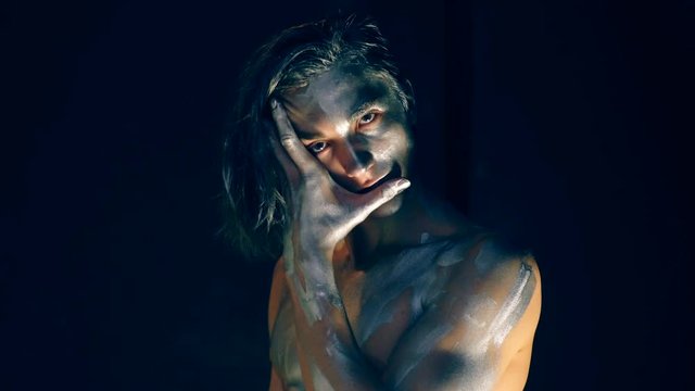 The guy with a gray body copy closes his face with his hand on a black background. Concept of posing for the camera.