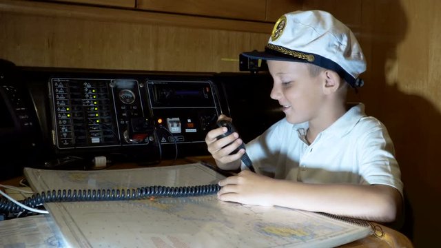 child skipper talking on walkie-talkie radio in cockpit on ship