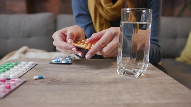 Close up of hand woman take many different spinning drugs background drink water lying on sofa fever in home feel unhappy flu sick adult cold illness person sickness virus portrait slow motion pills