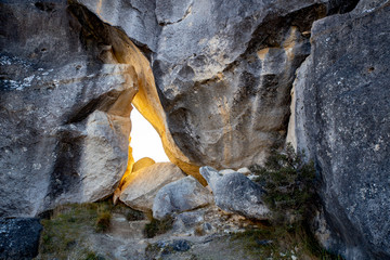 A gap in a limestone rock wall allows the early morning sunlight to filter through