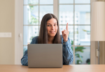 Young woman using laptop at home surprised with an idea or question pointing finger with happy...