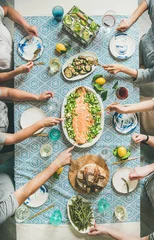 Fotobehang Family or friends summer party or seafood dinner. Flat-lay of group of mutinational people with different skin color at big table eating delicious food together. Summer gathering or celebration © sonyakamoz