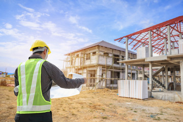 Professional engineer architect worker with protective helmet and blueprints paper at house building construction site