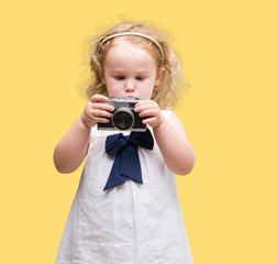 Fototapeta premium Beautiful blonde toddler taking pictures with vintage camera