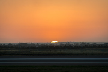 The sun just about to sink into the horizon with a rich orange sky in rural Victoria Australia