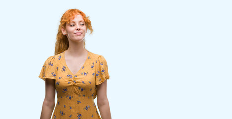 Young redhead woman smiling looking side and staring away thinking.