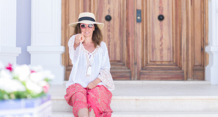 Middle age brunette woman wearing summer hat on vacations pointing with finger to the camera and to you, hand sign, positive and confident gesture from the front