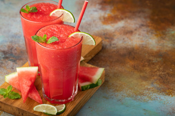 Watermelon slushie with lime, summer refreshing drink in tall glasses on a blue rusty background. with copy space