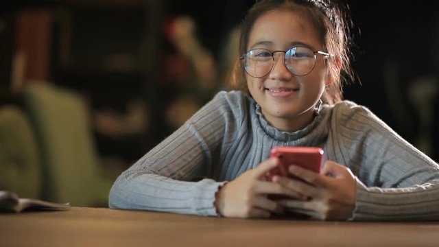 asian teenager chatting on smart phone and toothy smiling with happiness emotion