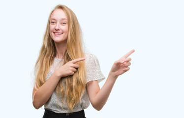 Blonde teenager woman wearing moles shirt smiling and looking at the camera pointing with two hands...