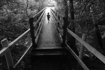 Small boy running across a bridge into the light