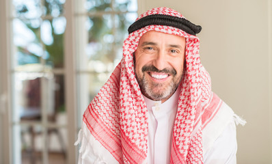 Middle age arabian man at home with a happy face standing and smiling with a confident smile showing teeth